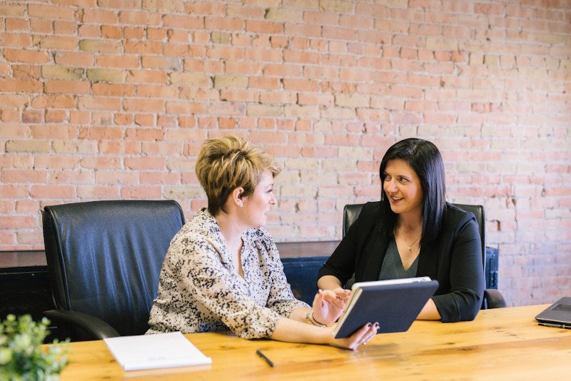 Two women having a discussion in an office with a tablet computer
